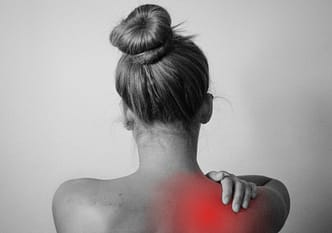 shoulder pain a person with the hair in a bun